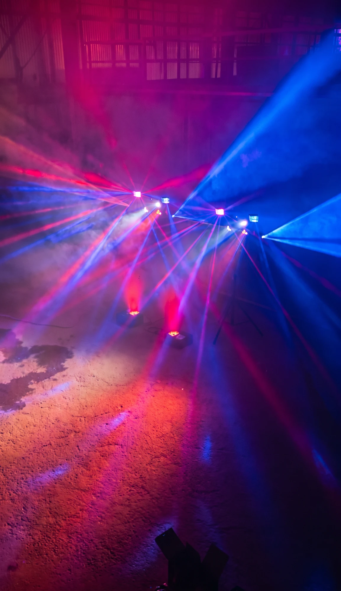 Lichtbars met rode en blauwe stralen en rook tijdens een feest in een loods