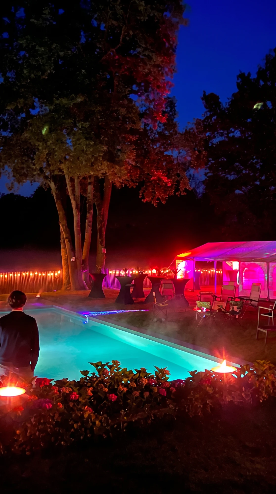 Tuinfeest bij een verlicht zwembad met statafels, sfeerverlichting en partytent in de Kempen