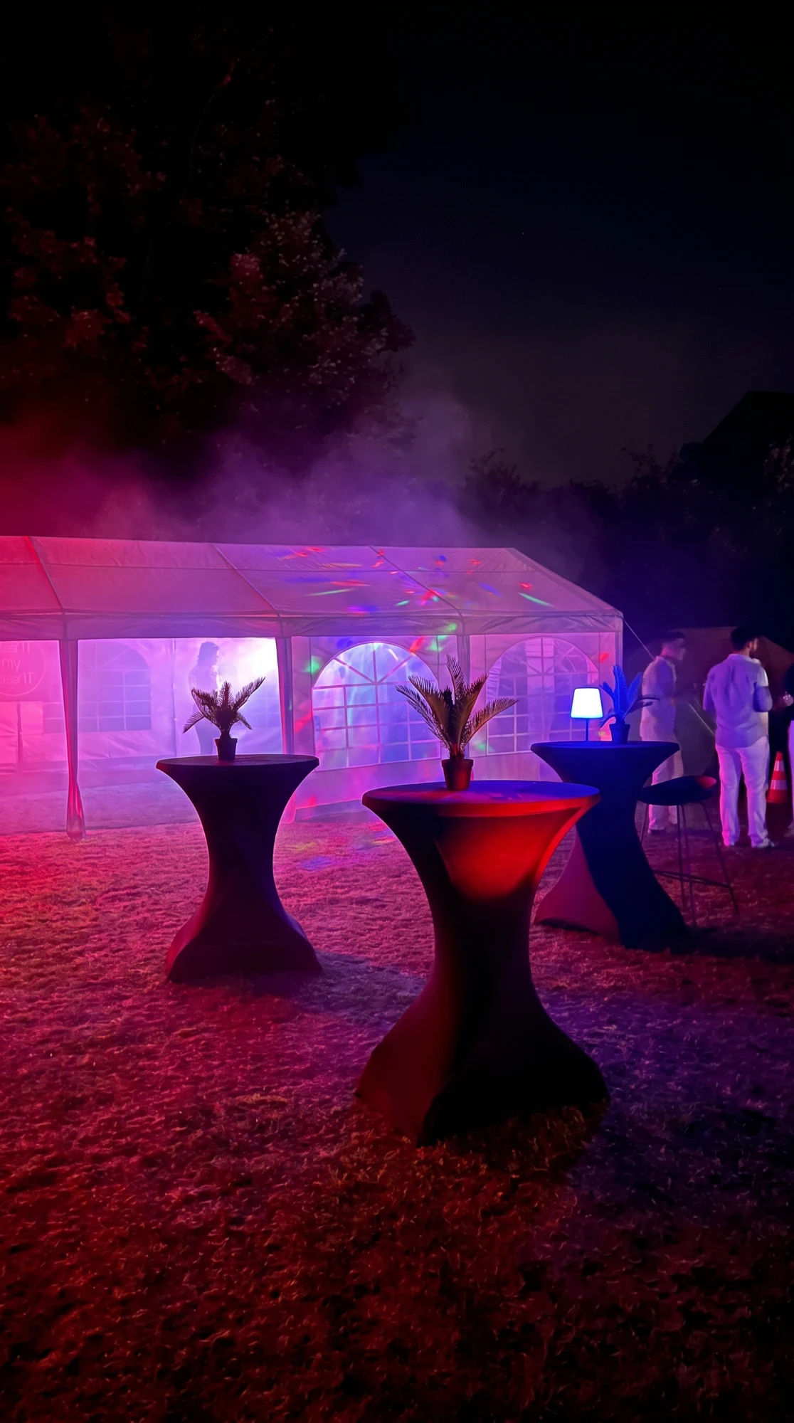 Statafels met zwarte stretchhoes voor een partytent met roze en paarse sfeerverlichting